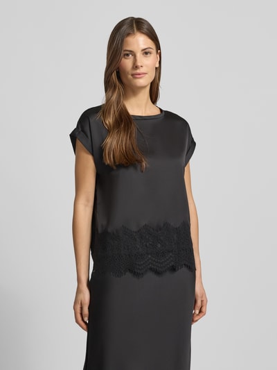 Frauenmodel trägt T-Shirt mit Rundhalsausschnitt Modell 'ELLETTE' von Vila aus schwarzem Satin mit Spitzenbesatz, lockerer Schnitt, Nahaufnahme Oberkörper.