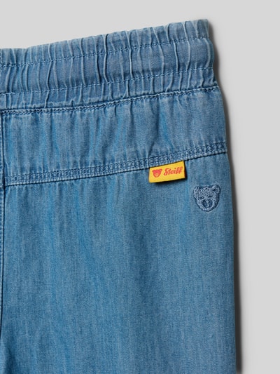 Produktfoto, Jeans mit elastischem Bund und Kordelzug von Steiff z niebieskiej bawełny, detal z logo, wyhaftowany motyw, szerokość w rozmiarze 116: 30 cm, długość wewnętrzna nogawki 45 cm