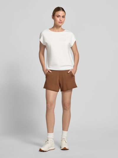 Kobiece model prezentuje damski t-shirt z mieszanki wiskozy z dodatkiem streczu, krój regular fit, model 'Uvalerie' od Someday, okrągły dekolt, krótkie rękawy, długość tyłu w rozmiarze 36: 57 cm, widok całej sylwetki z przodu