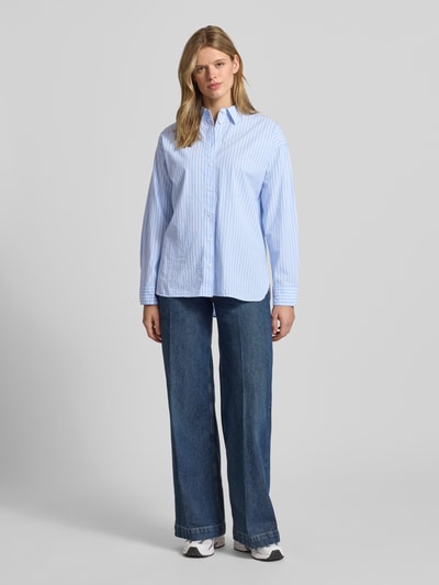 Vrouwenmodel draagt Basic Hemdbluse aus reiner Baumwolle van REVIEW in relaxed fit, all-over look, overhemdkraag, knoopsluiting, puur katoen, ruglengte maat S 65 cm, mouwlengte maat S 56 cm, kleuren lichtblauw en wit, rechte lijnen, gladde stof, Ganzkörperansicht von vorne.