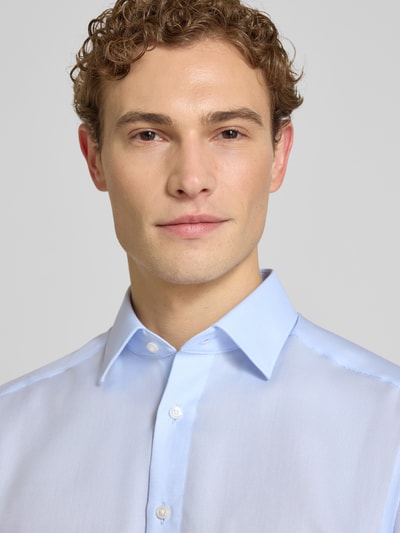Męski model nosi Modern Fit Business-Hemd aus Baumwolle mit Kentkragen od OLYMP, jasnoniebieska, gładka struktura, listwa guzikowa, bawełna, długość tyłu w rozmiarze 40: 80 cm, szerokość ramion w rozmiarze 40: 43 cm, długość rękawów w rozmiarze 40: 64 cm, zbliżenie górnej części ciała