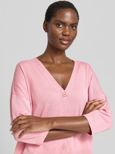 Frauenmodel trägt Relaxed Fit Cardigan aus Viskose-Mix in Strick-Optik von Comma in Rosa mit V-Ausschnitt, 3/4-Arm, Knopfleiste, Nahaufnahme Oberkörper.
