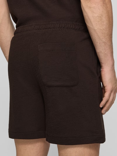 Mężczyzna nosi Regular Fit Sweatshorts aus reiner Baumwolle von Lacoste, brązowy kolor, logo, elastyczny pas, tkanina typu crêpe, zdjęcie tyłem, detaliczne ujęcie