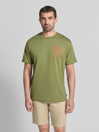 Männermodel trägt T-Shirt mit Label-Print und Rundhalsausschnitt von Scotch & Soda in olijfgroen, puur katoen, regular fit, ruglengte maat M 72 cm, voorkant, Ganzkörperansicht von vorne.