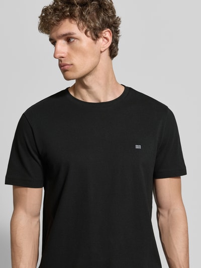 Männermodel trägt T-Shirt aus Baumwolle mit Rundhalsausschnitt von Christian Berg Men in Schwarz mit Label-Detail, Regular-Fit, Nahaufnahme Oberkörper.