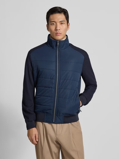 Männermodel trägt Jacke mit Stehkragen von Christian Berg Men in Dunkelblau mit Reißverschluss, Reißverschlusstaschen, Regular-Fit, Ganzkörperansicht von vorne. Rückenlänge 26 cm, Schulterbreite 19 cm, Brustweite 19 cm, Ärmellänge 26 cm, gerippte Abschlüsse.