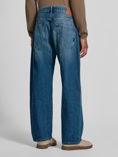 Männermodel trägt Loose Fit Jeans Modell 'THE PITCH' von Scotch & Soda in Blau mit Used-Look, Baumwolle, Ganzkörperansicht Rückansicht.
