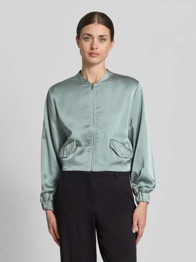 Vrouwenmodel draagt Blouson met Pattentaschen und Reißverschluss van Zero in lichtgroen materiaalmix met stretch, straight fit, opstaande kraag, ritssluiting, zij-klepzakken, elastische mouwboord, ruglengte maat 36: 40 cm, borstwijdte 38 cm, mouwlengte 57 cm, Ganzkörperansicht van voren.