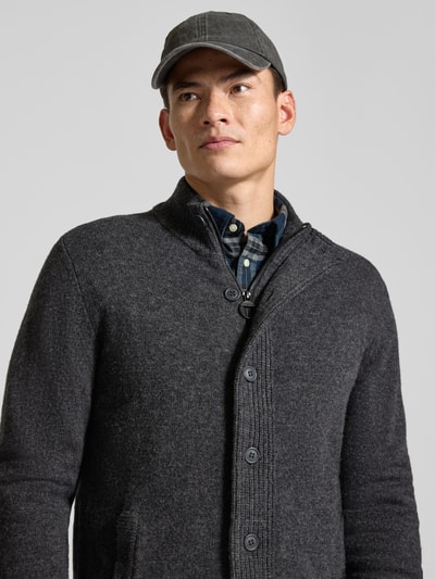 Männermodel trägt Cardigan mit Stehkragen Essential PATCH van BARBOUR, effen kleuren, gebreide look, opstaande kraag, doorlopende knoopsluiting, lange mouw, mouw- en rompzoom geribd, Ganzkörperansicht von vorne.