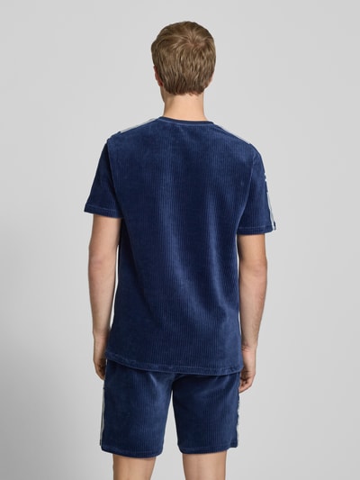 Męski model nosi T-Shirt mit Logo Modell 'MADORI' von Ellesse, mieszanka bawełny z dodatkiem streczu, krój regular fit, okrągły dekolt, długość tyłu w rozmiarze M: 66 cm; widok całej sylwetki z tyłu.