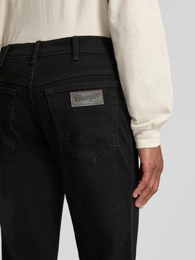 Männermodel trägt Straight Fit Jeans im 5-Pocket-Design Modell 'Texas' von Wrangler in Schwarz, Nahaufnahme Rückansicht, Baumwoll-Mix mit Stretch-Anteil, Label-Detail sichtbar.
