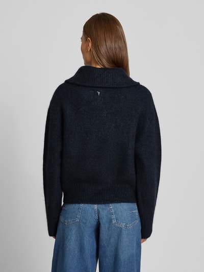 Frauenmodel trägt Strickjacke aus Mohair-Mix mit Label-Detail Modell 'Hulda' von MOS MOSH, dunkles Blau, lockere Passform, Rückenansicht, KI-modifiziertes Bild.