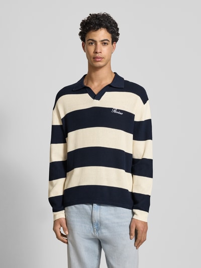 Männermodel trägt Regular Fit Strick-Poloshirt mit Block-Streifen von REVIEW aus reiner Baumwolle, Logo-Bestickung, Ganzkörperansicht von vorne.