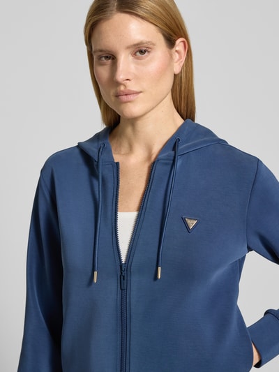 Vrouwenmodel draagt Regular fit sweatshirt met logo-applicatie model 'Olympe' van Guess, elastische mix met modal, kap, rits, close-up bovenlichaam.
