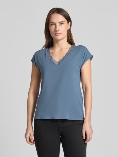 Modelka nosi Regular Fit T-Shirt mit Spitzenkragen Modell 'BELLA' von Vero Moda, unikatowy niebieski kolor, jersey-stretch, krój regular fit, V-dekolt z koronką, krótki rękaw, materiał wiskozowy, optyka jednolita, widok całej sylwetki z przodu.