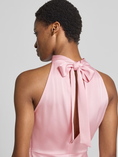 Vrouwenmodel draagt jurk van satijn Model 'RHEO' van Samsøe Samsøe in roze, halter met strik, getailleerd model, detailopname rug.