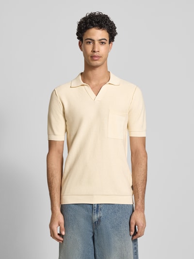 Męski model nosi Slim Fit Poloshirt in Strick-Optik od Replay, bawełna, krój slim fit, kremowy kolor, kieszeń na piersi, widok całej sylwetki z przodu.