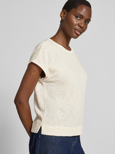 Frauenmodel trägt T-Shirt mit Strukturmuster und Rundhalsausschnitt von Christian Berg Woman aus Baumwoll-Mix im Regular-Fit, Rückenlänge 55 cm, Cremefarbe, Nahaufnahme Oberkörper.