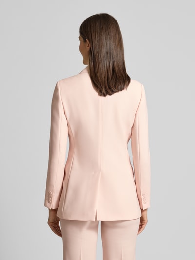 Frauenmodel trägt Regular Fit Longblazer aus reiner Schurwolle von Max Mara Studio in zartem Rosa, doppelte Knopfleiste, Pattentaschen, Ganzkörperansicht Rückansicht.