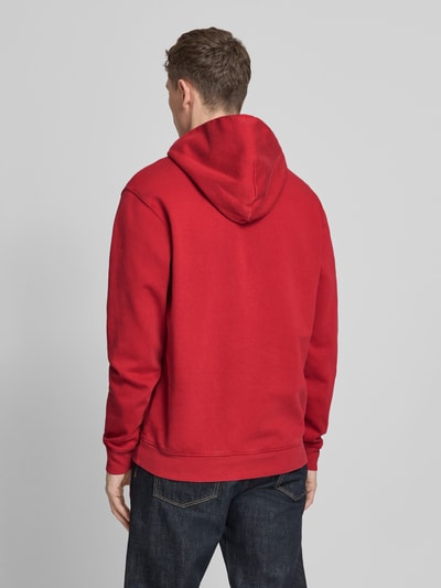 Mannenmodel draagt Hoodie mit Logo und Känguru-Tasche van GAP in effen rood, regular fit katoenmix, productdetails zichtbaar, volledige rugaanzicht.