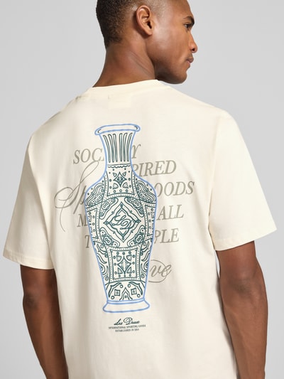 Męski model nosi T-Shirt mit rückseitigem Motiv-Print Modell 'Ben Faience' von Les Deux z czystej bawełny, prosty krój, kremowy, nadruk statement z tyłu, widok z tyłu, ujęcie całopostaciowe