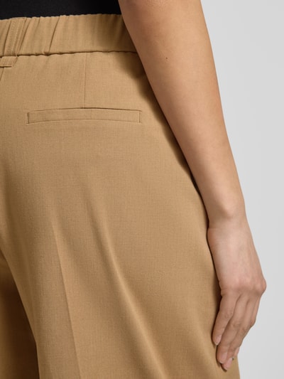 Frauenmodel trägt Barrel Fit Hose Modell 'Moira Bloom' von OPUS PANTS in Beige, Baumwoll-Mix mit Bügelfalten, Nahaufnahme Rückansicht.