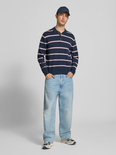 Männermodel trägt Langarm-Poloshirt aus Viskose-Mix im Allover-Look von JACK & JONES, dunkelblau mit Streifen, Ganzkörperansicht von vorne