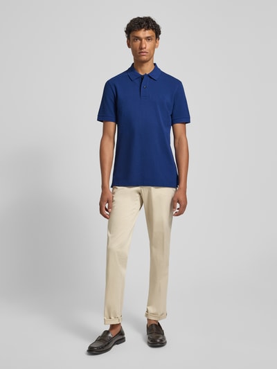 Männermodel trägt Regular Fit Poloshirt aus reiner Baumwolle Modell 'PALLAS' von BOSS in Unifarben, Piqué-Struktur, Ganzkörperansicht von vorne.