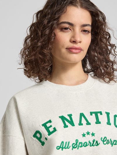 Kobiecy model nosi Sweatshirt mit Label-Stitching und Rundhalsausschnitt von P.E Nation, mieszanka bawełny, krój relaxed fit, prążkowany okrągły dekolt, wyhaftowane logo, opuszczone ramiona, prążkowane wykończenia, zbliżenie na górną część ciała.