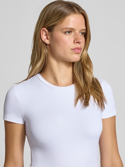 Vrouwenmodel draagt wit slim fit t-shirt met ronde hals model 'LULA' van PIECES, dames t-shirt, close-up bovenlichaam.