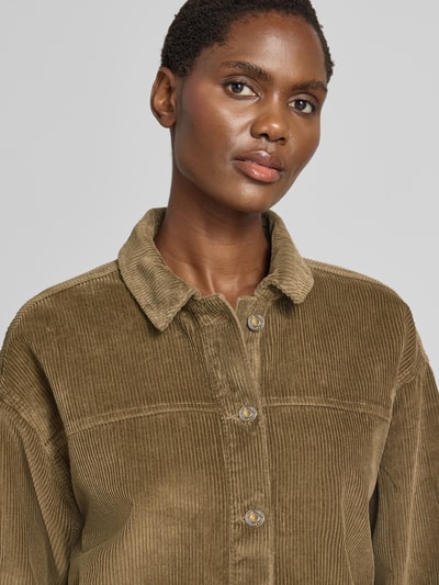 Frauenmodel trägt Relaxed Fit Langarmbluse aus reiner Baumwolle Modell 'JAMIE' von VERO MODA in Olivgrün mit Cordstruktur, Nahaufnahme Oberkörper.