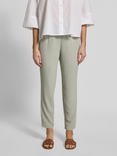 Frauenmodel trägt Jogpants mit elastischem Bund und Eingrifftaschen von Christian Berg Woman in hellem Grün, Slim Fit, Ganzkörperansicht von vorne.
