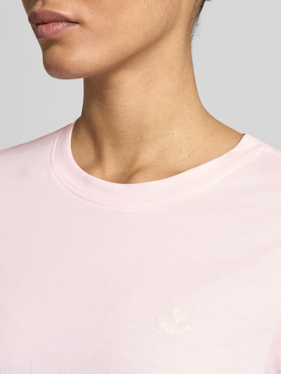 Frauenmodel trägt Regular Fit T-Shirt aus reiner Baumwolle von s.Oliver RED LABEL in zartem Rosa, Stickerei-Detail, Rundhals, Nahaufnahme Oberkörper.