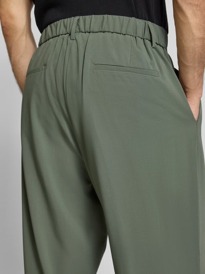 Männermodel trägt Stoffhose mit Label-Detail von Antony Morato in Oliv, Material-Mix mit Viskose-Anteil, Gesäßtaschen, Nahaufnahme Rückansicht.
