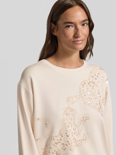 Vrouwenmodel draagt Sweatshirt mit Stitchings und Pailletten van Milano Italy, modal-mix met stretch, regular fit, ronde hals, crèmekleur, details met pailletten, close-up bovenlichaam.