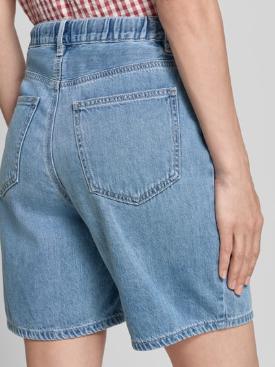 Frauenmodel trägt Regular Fit Bermudas aus Baumwoll-Lyocell-Mix Modell 'VILLA' von Vero Moda, Denim-Optik, 5-Pocket-Design, Ganzkörperansicht Rückansicht.