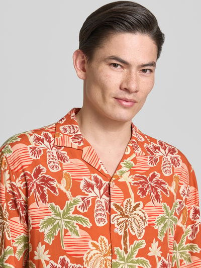 Männermodel trägt Regular Fit Freizeithemd aus Viskose-Lyocell-Mix mit Reverskragen von MCNEAL, Allover-Look, Nahaufnahme Oberkörper. Rückenlänge bei Größe M: 73 cm, Schulterbreite: 51 cm, Ärmellänge: 26 cm, Knopfleiste, orange mit grün-rotem Muster, glatte Textur.