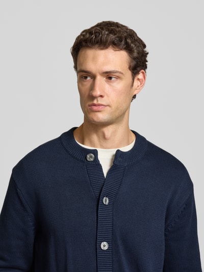 Männermodel trägt Regular Fit Cardigan aus reine Baumwolle von Selected in Dunkelblau, Struktur grobstrick, Nahaufnahme Oberkörper.