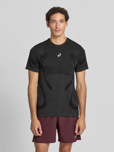 Männermodel trägt schwarzes Slim Fit RUNNING T-Shirt Modell 'ROAD' von ASICS, metallic Label-Print, Rundhalsausschnitt, Ganzkörperansicht von vorne. Rückenlänge bei Größe M: 72 cm.