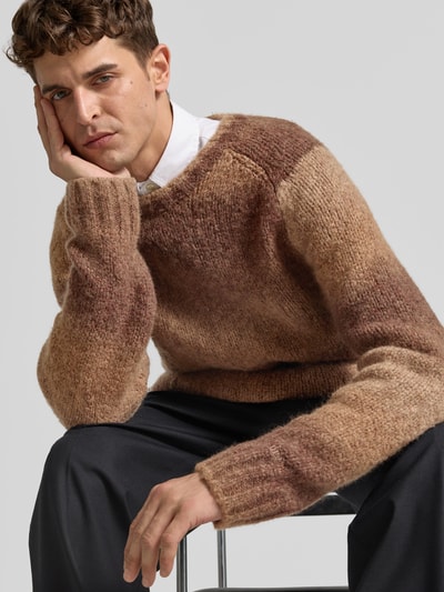 Männermodel trägt Pullover aus Woll-Mix von Forét in Brauntönen, gerader Schnitt, Rundhalsausschnitt, Raglanärmel, Nahaufnahme Oberkörper.