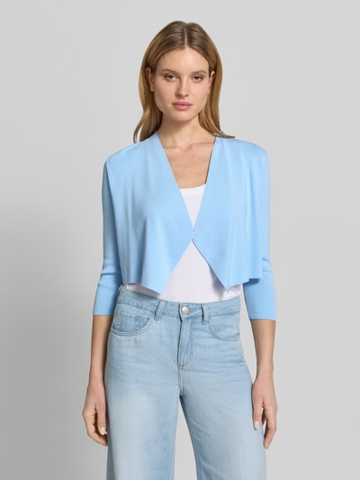 Frauenmodel trägt Strickjacke in offener Passform mit 3/4-Arm von comma, hellblau, glatte Textur, locker geschnitten, Ganzkörperansicht von vorne.