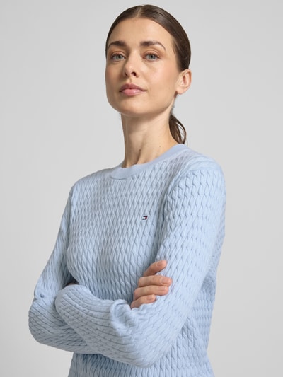 Modelka nosi Slim Fit Pullover aus reiner Baumwolle von Tommy Hilfiger, jednolity kolor, imitacja dzianiny, ścieg warkoczowy, detal z logo, okrągły dekolt, długi rękaw, prążkowane wykończenia, bawełna; zbliżenie na górną część ciała