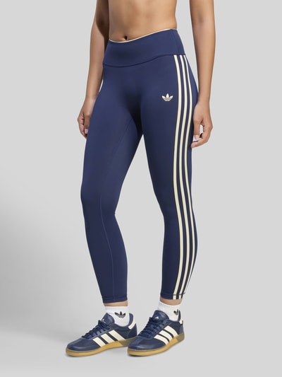 Frauenmodel trägt Slim Fit Sport-Leggings mit CLIMACOOL Technologie von adidas Training, dunkelblau mit weißen Streifen, Nahaufnahme Unterkörper.