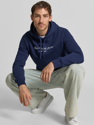 Męski model trägt Relaxed Fit Hoodie aus mieszanka bawełny von Polo Ralph Lauren, ciemnoniebieski, jasnoniebieskie spodnie, Ganzkörperansicht von vorne.