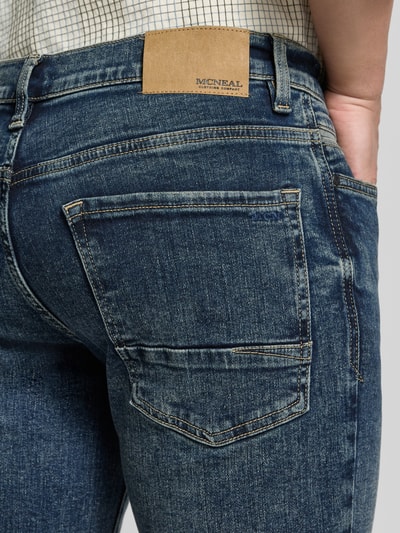 Męski model nosi Regular Fit Jeans mit Eingrifftaschen von MCNEAL, mieszanka bawełny i elastanu, efekt znoszenia, wpuszczane kieszenie, Szerokość w rozmiarze 32/32: 45 cm, Długość wewnętrzna nogawki w rozmiarze 32/32: 80 cm, widok z tyłu zbliżenie na pośladki.
