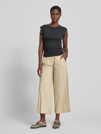 Frauenmodel trägt Culotte mit Eingrifftaschen Modell 'Jenny' von TONI in Beige, weiter Schnitt, Bügelfalten, Nahaufnahme Ganzkörperansicht von vorne.