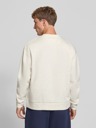 Męski model nosi Regular Fit Sweatshirt mit Baumwoll-Anteil od JACK & JONES, kolor jasny beż, mieszanka bawełny, okrągły dekolt, elastyczne wykończenia, krój regular fit, długi rękaw, długość tyłu 65 cm, długość rękawów 59 cm, widok całej sylwetki od tyłu.