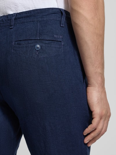 Männermodel trägt Leinenhose mit Schnürung und achterzakken van MCNEAL, regular fit, zuiver linnen, detailaufnahme achterkant.