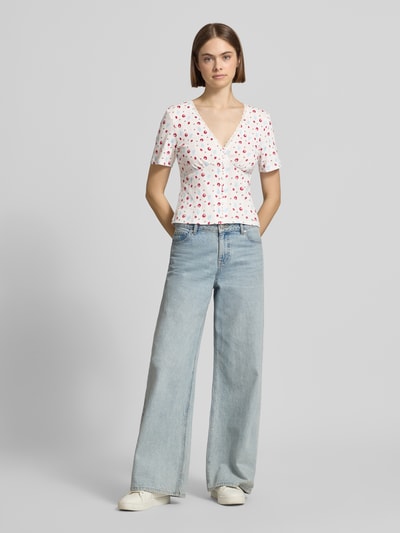 Frauenmodel trägt Blusenshirt in Pointelle-Optik Modell 'Vianne' von OH APRIL, Reine Baumwolle, enger Schnitt, rote Punkte, Ganzkörperansicht von vorne.