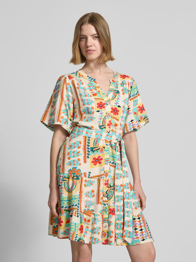 Kobiece model prezentuje sukienka mini z mieszanki wiskozy i lnu od Apricot, kwiatowy nadruk na całej powierzchni, listwa guzikowa, rękaw o dł. 1/2, odpinana materiałowa tasiemka, dekolt z lamówką, krój taliowany; długość tyłu w rozmiarze S: 85 cm, szerokość w rozmiarze S: 52 cm, długość rękawów w rozmiarze S: 28 cm; zdjęcie całej sylwetki z przodu.